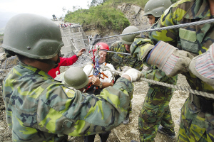 13日，臺灣高雄縣六龜鄉(xiāng)新開村有20多戶遭泥石流淹沒。圖為軍人正陸續(xù)將生還者救出。
