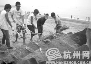 大連市金石灘國賓浴場，工作人員將帶有油污的沙子清理掉。