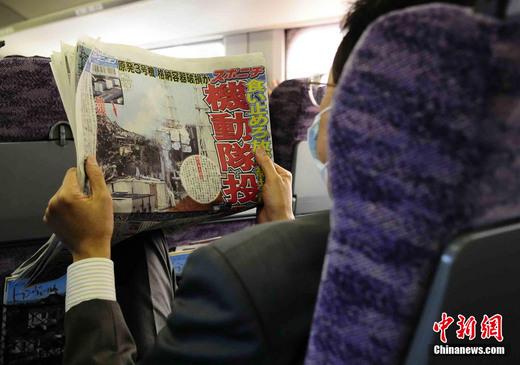 3月17日下午，在一列前往東京的新干線列車上，一名日本人在閱讀關于福島核電站三號機組最新狀況的報道。中新社發(fā) 侯宇 攝