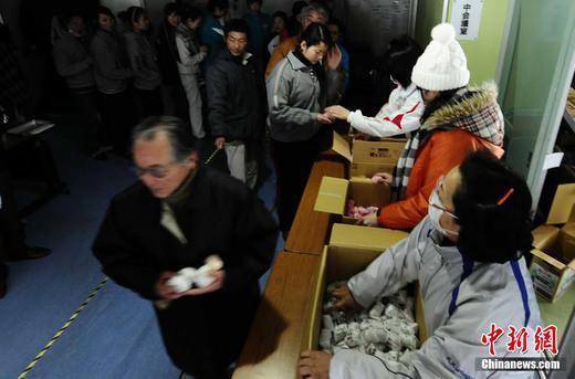 3月16日，在日本巖手縣大船渡地區(qū)公民會館避難的民眾排隊領取食物。中新社發(fā) 侯宇 攝