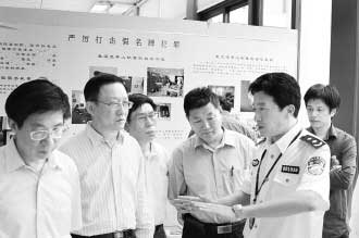 圖為公安部經(jīng)偵局副局長高峰(右)向公安部特邀監(jiān)督員們介紹“亮劍”行動(dòng)展覽情況。 