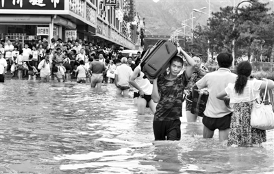 昨日，一名消防戰(zhàn)士在秦皇島市山海關(guān)火車站站前廣場(chǎng)涉水幫助旅客運(yùn)送行李。 新華社發(fā)