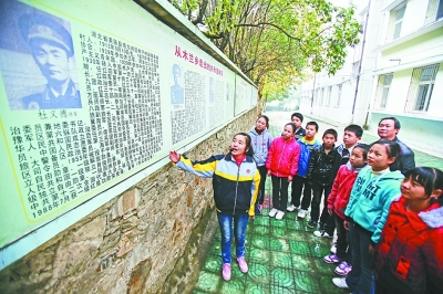 上圖：學(xué)校文化墻前，小講解員講述開國將軍杜義德的故事。記者何曉剛 攝