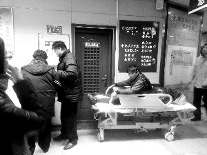 受傷工人小王坐在病床上候診。