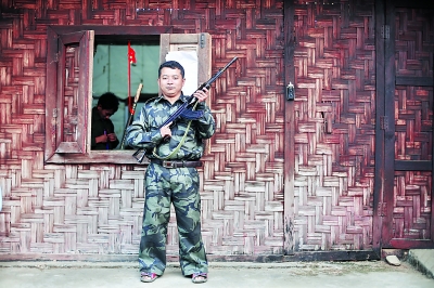 老三手持自己在前線用的半自動(dòng)步槍站在居住的小屋外。