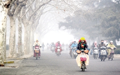 昨天上午，中原路，行人在霧霾中騎車出行，很多行人戴上了口罩。