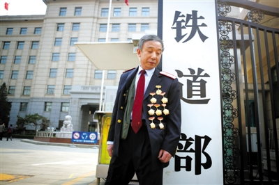 3月14日，鐵道部大門口，一位胸前掛著多枚勛章的鐵道部老職工與鐵道部牌子合影。 新京報記者 侯少卿 攝