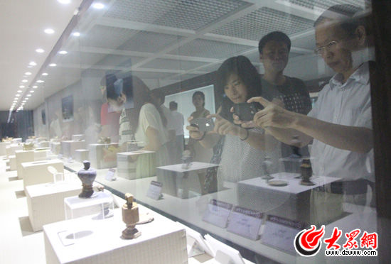 采訪團(tuán)的記者們拍攝隨元代古沉船共同挖掘出土的文物，他們對(duì)這些文物很感興趣。